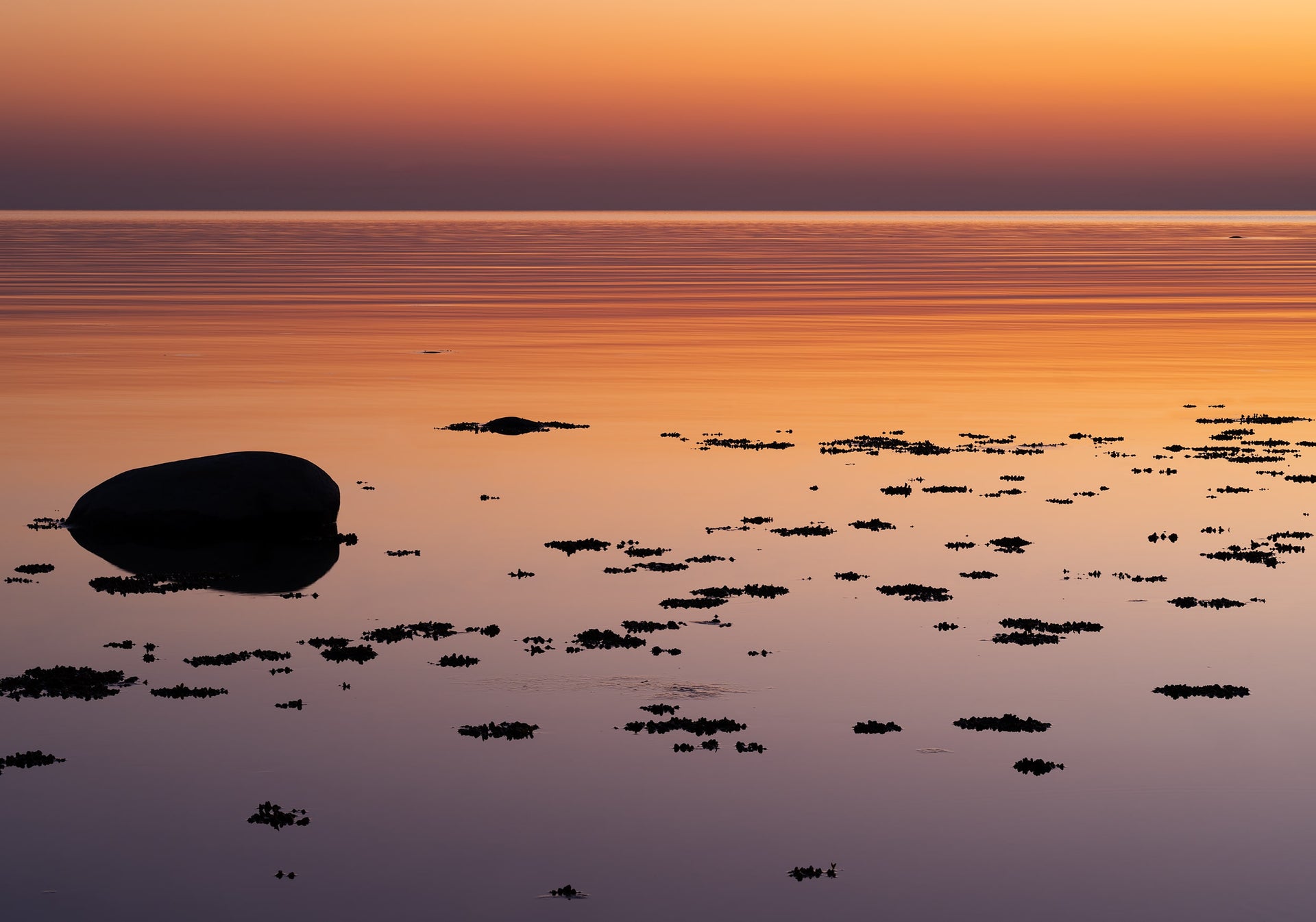 Calm Sea at Sunset with Reflections and Rocks