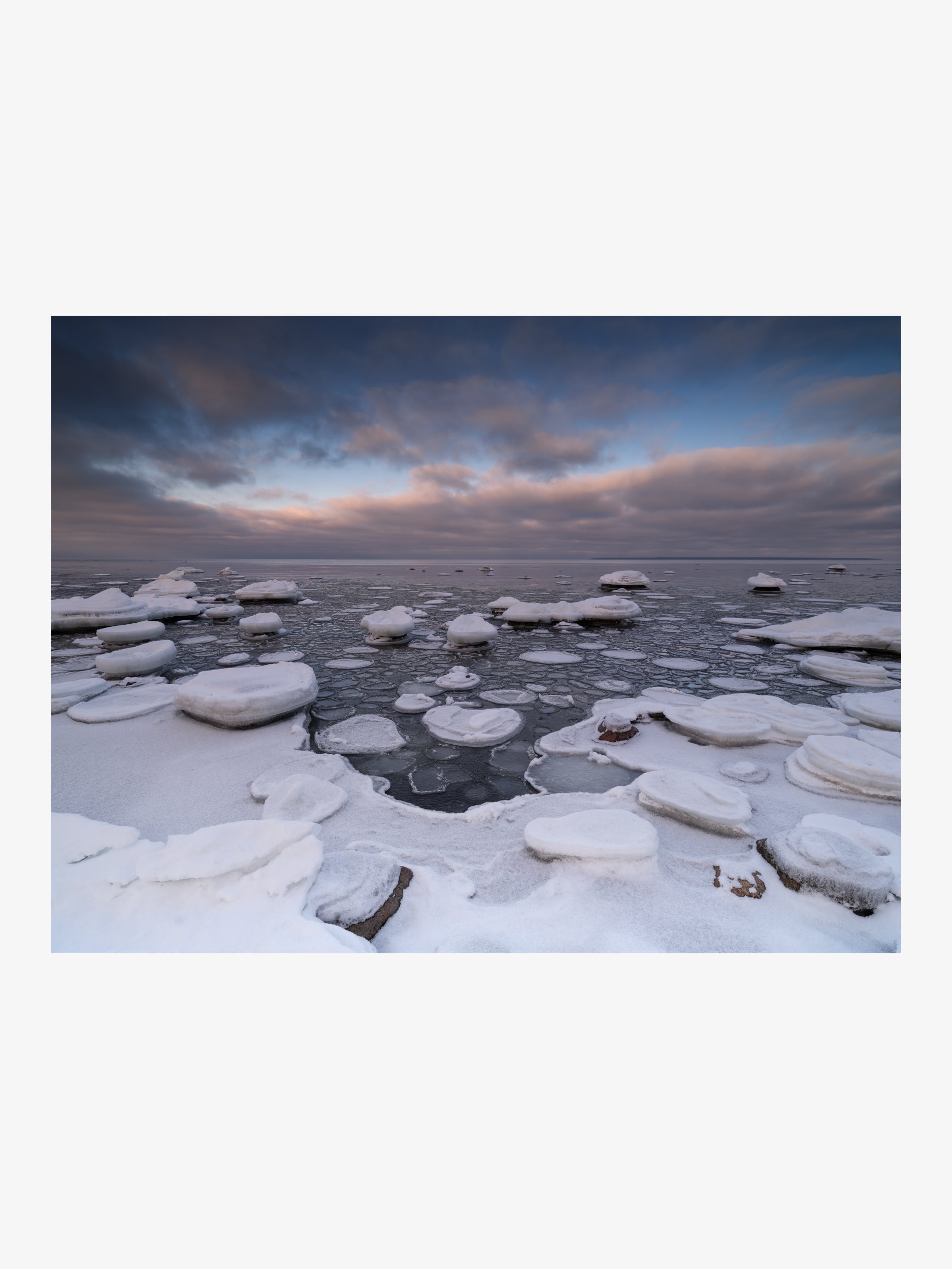 Pancake Ice and Snow-Covered Rocks on a Winter Coast