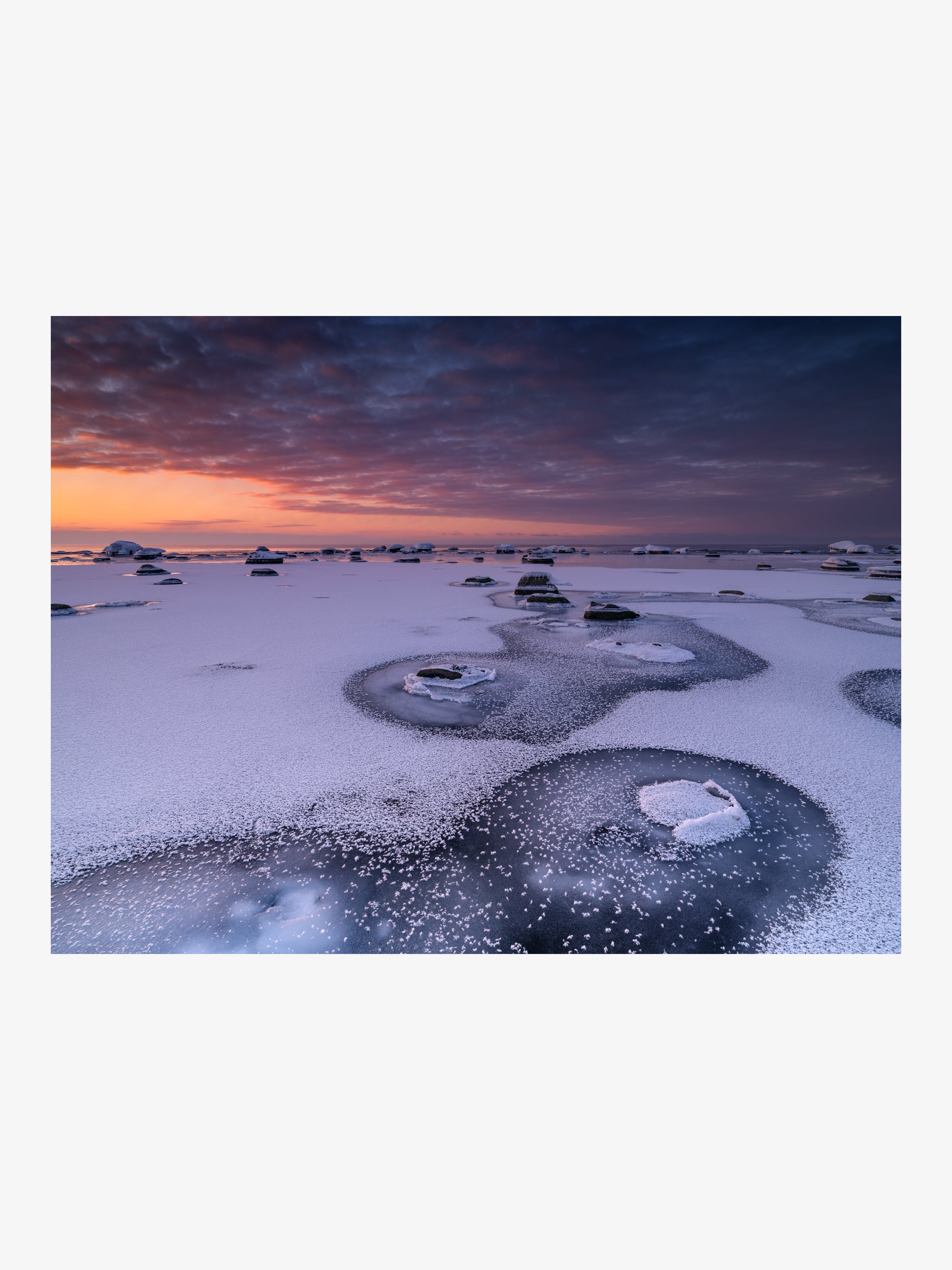 Frost Halos Around Rocks on a Frozen Shore at Sunset