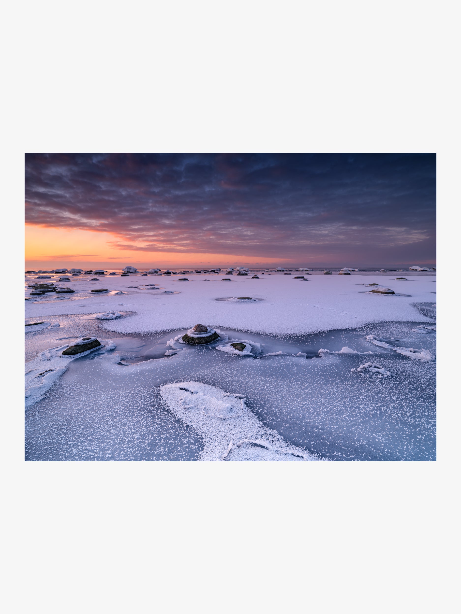 Hundreds of Snow-Dusted Rocks on a Frozen Shore at Dusk