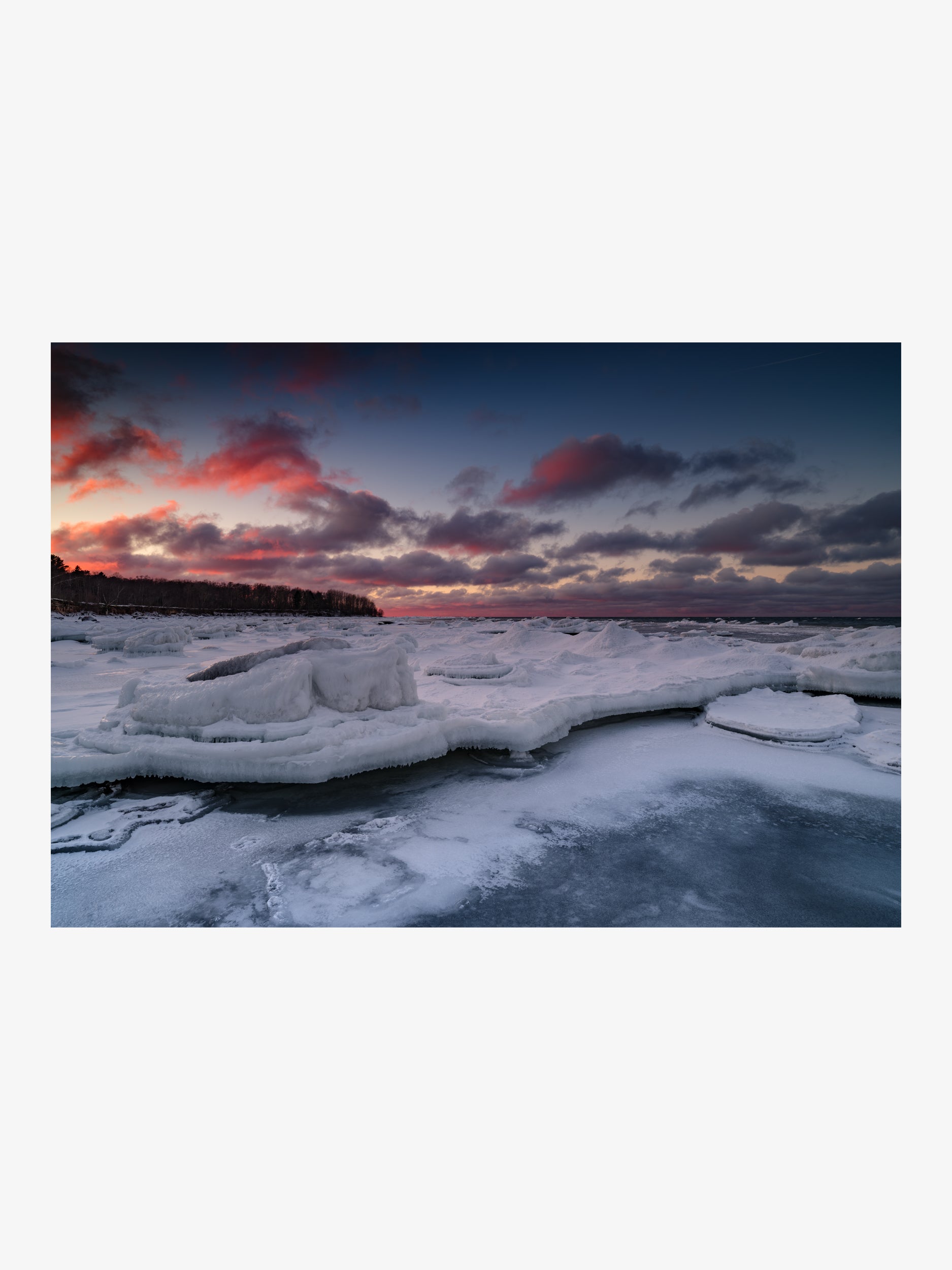 Massive Ice Ridges on the Shore Under Red Clouds